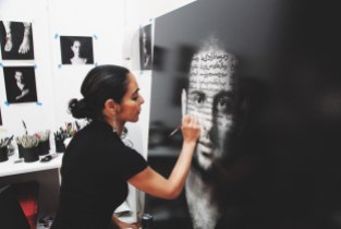 Shirin Neshat writing Persian poetry on the image of a young Iranian.